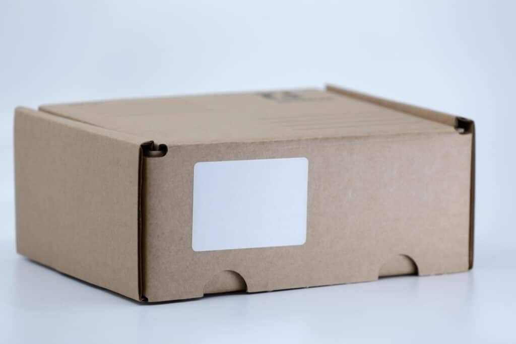Caja de cartón de envío sobre una mesa blanca, representando una compra realizada en una tienda online